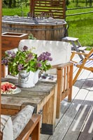 Flowers on garden table with hot tub in background 