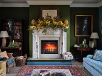 Lit fireplace with Christmas garland on mantlepiece 