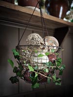 Hanging basket filled with festive baubles and decorated with ivy foliage 