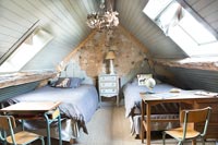 Exposed stone wall and pitched roof in modern country twin bedroom 