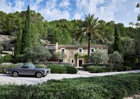 Exterior of stone country house with vintage car parked in driveway 