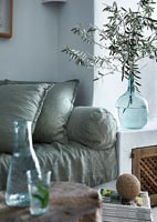 Blue glass vase of olive tree branches on side in modern country living room