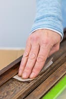 Woman rubbing down old wooden frame - memories notice board 