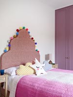 Modern childrens room with pompoms around headboard of bed 