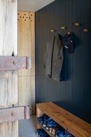 Bench shoe rack and coat hooks in modern country hallway 