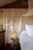 Decorative wooden ladder next to bed in country bedroom 