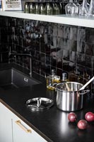 Modern kitchen with gleaming black tiled splashbacks 