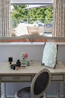 Dressing table in modern bedroom with view of terrace through window 