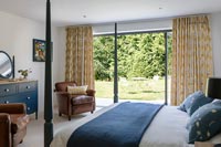 Four poster bed in modern bedroom with sliding doors to garden 