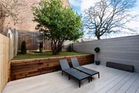 Split level modern courtyard garden with recliners on decked area 