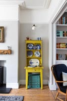 Small yellow painted dresser with display of blue and white plates 