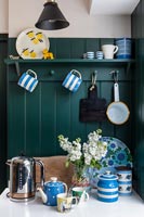 Blue and white crockery in modern kitchen with green painted wall 