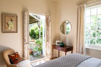 Country bedroom with open French doors to garden 
