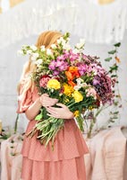 Young woman holding large bunch of cut flowers 