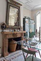 Carved wooden mantelpiece and large unusual mirror in eclectic dining room 