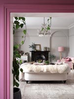 Pink painted wall with view into modern living room 
