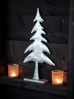Silver tree ornament flanked by tealight candles 