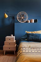 Dark blue painted walls and bedside cabinet in modern bedroom 
