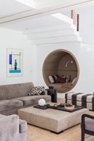 Circular alcove seat built in to modern living room wall under stairs 