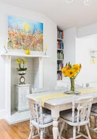 Colourful artwork above small fireplace in dining area