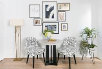 Modern table and chairs with display of framed artwork on wall 