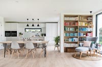 Modern kitchen-diner with bookshelves and reading chair in corner 