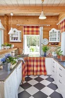 Country kitchen with checked floor and fabric skirts on cupboards 