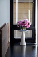 Pink roses in vase on white plinth 