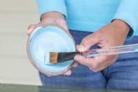 Woman using a brush to paint the saucer
