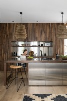 Girl in an open-plan modern kitchen with built-in cabinet in wood and stainless steel