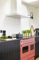 Modern country kitchen with dark cupboards, units, black wall lights, pink Aga and wooden floors