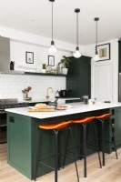 Contemporary kitchen with green cupboards, island, pendants, and leather bar stools