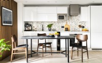 A white modern contemporary kitchen with a black marble dining table, mid-century chairs, a terrazzo splash back and black taps