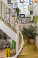 Colourfully eclectic staircase with large display of framed artwork