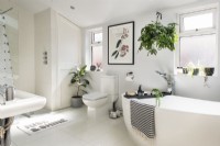 Modern bathroom with artwork on wall and lots of houseplants 