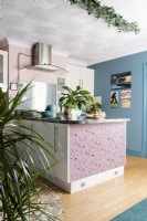 View into pink and blue kitchen with island unit