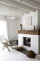 White painted living room with wicker chair next to fireplace
