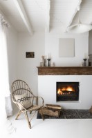 Wicker chair next to lit fireplace in white country living room