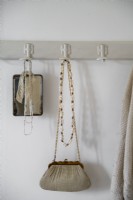 Detail of handbag and jewellery on old wall mounted coat hooks