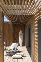 Surfboard against wall and recliners on decking - summer