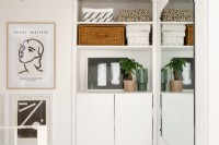 Bright white upstairs hallway with built-in storage and cupboards. Framed pictures hang on the walls.