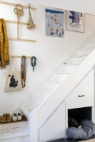 White painted staircase with built-in storage and dog bed. Artwork and hooks hang on the wall. 