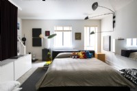 Modern bedroom with displays of artwork and collection of stuffed Sesame Street animals on bed.