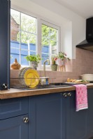 Blue kitchen units and sink with pink tiles