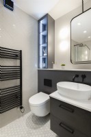 Modern bathroom toilet and basin with lit shelving
