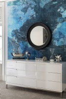 White chest of drawers in front of wall with a vinyl world mural.