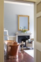 View in to bedroom with large copper bath and gilt mirror.