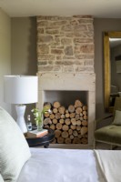 Wood stored in fireplace of contemporary bedroom.  Stone fireplace and pale green colour scheme