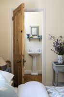 Pine door leading to en-suite bathroom, from cream painted vintage style bedroom