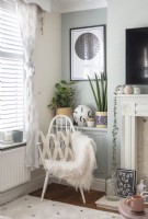 Cushion and fluffy blanket on wooden armchair in modern living room
